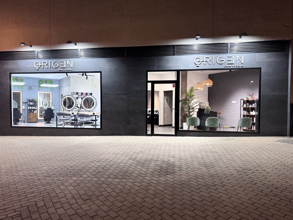 Fachada de ORIGEN Hair Studio iluminada de noche en la calle Uruguay, El Bercial, Getafe